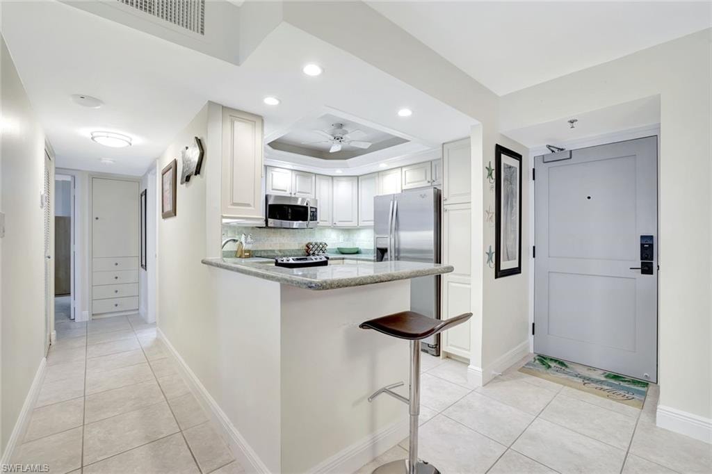 Kitchen featuring light stone counters, a peninsula, light tile patterned floors, recessed lighting, and stainless steel appliances
