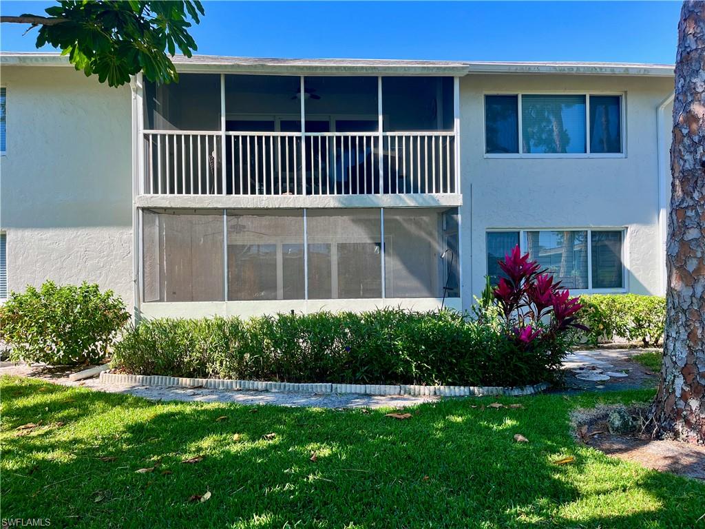 Rear view of property featuring a lawn and a balcony