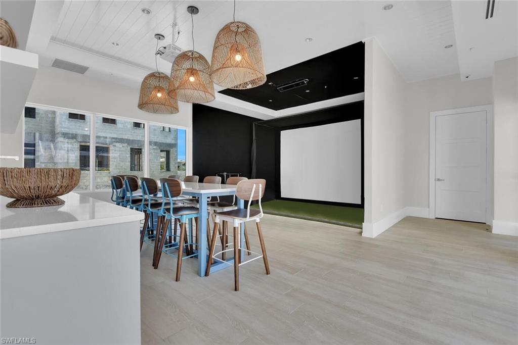 Dining space featuring light hardwood / wood-style flooring, a towering ceiling, and golf simulator