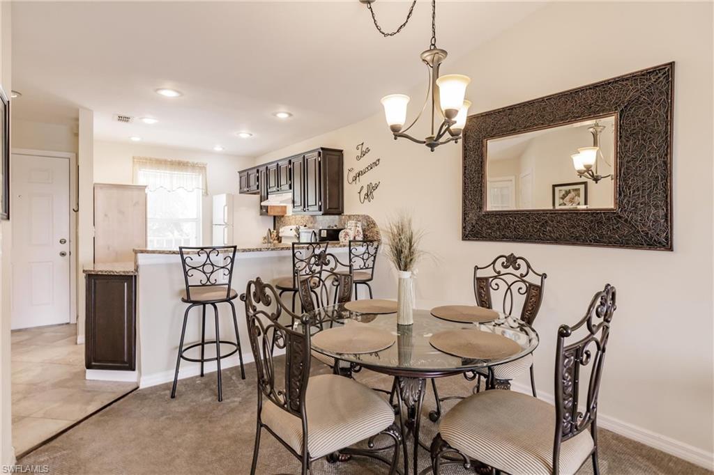 Dining space featuring light carpet and a notable chandelier