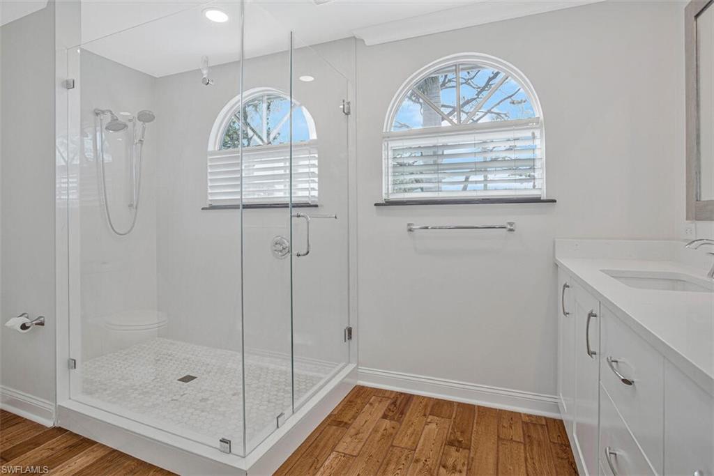 Full bath featuring vanity, light wood finished floors, and a stall shower