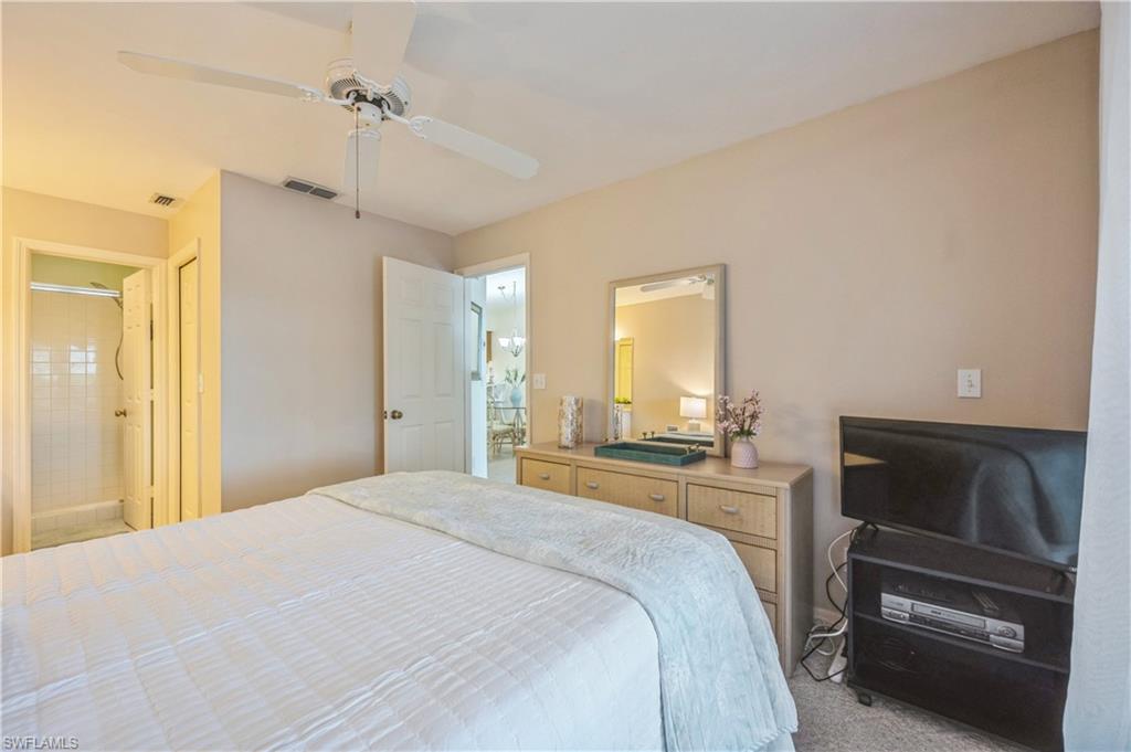 Carpeted bedroom featuring ceiling fan and connected bathroom