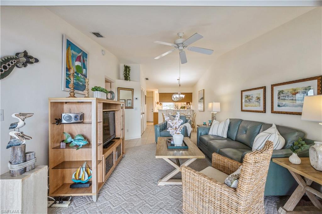 Living area featuring a ceiling fan, a chandelier, and tile patterned flooring