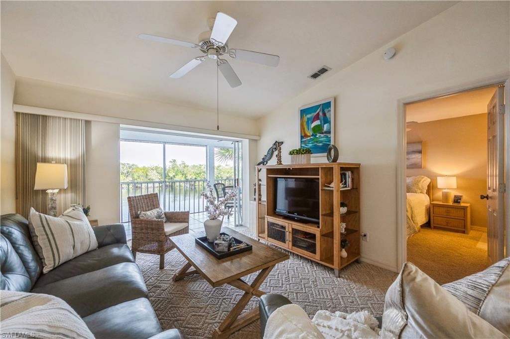 Living room featuring vaulted ceiling, carpet flooring, and ceiling fan