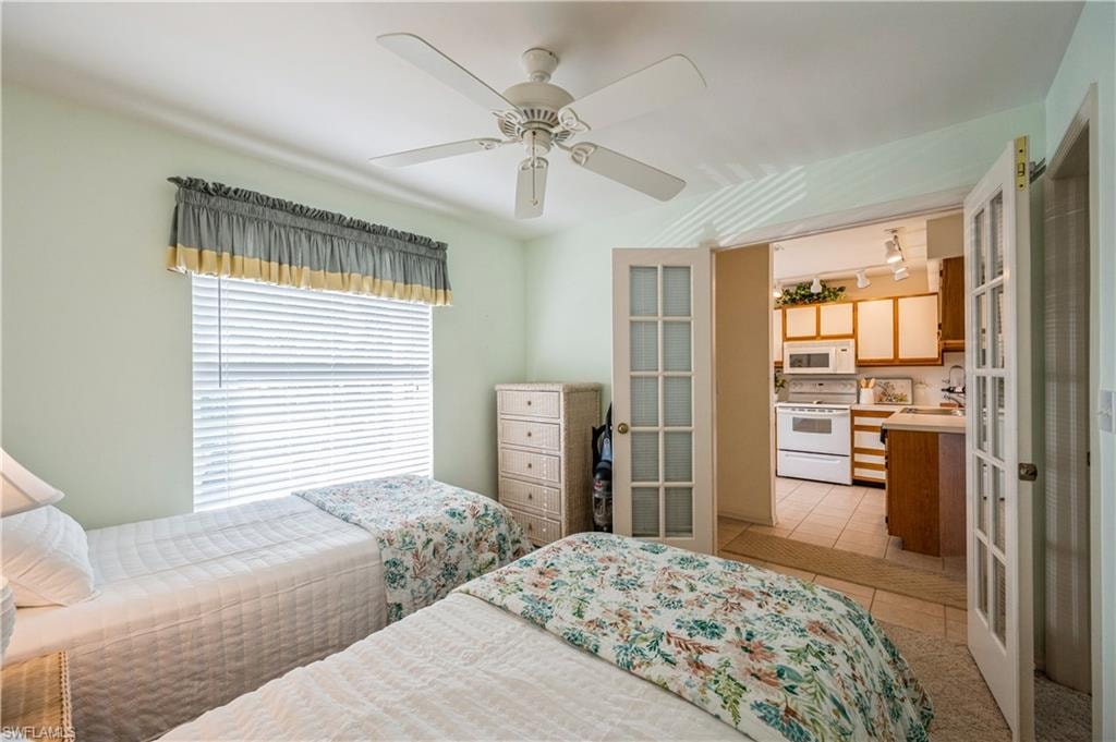 Bedroom with light tile patterned flooring, ceiling fan, and french doors