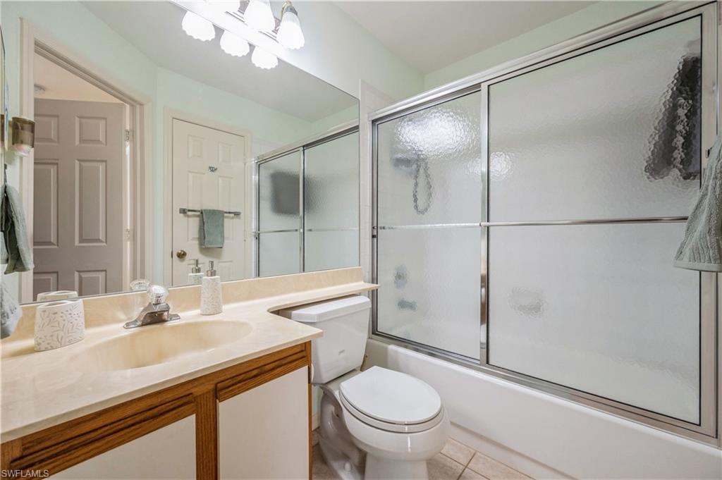Bathroom with vanity, enclosed tub / shower combo, and light tile patterned floors