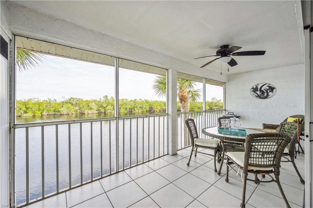 Sunroom / solarium with a water view, ceiling fan, outdoor dining space, and view of scattered trees
