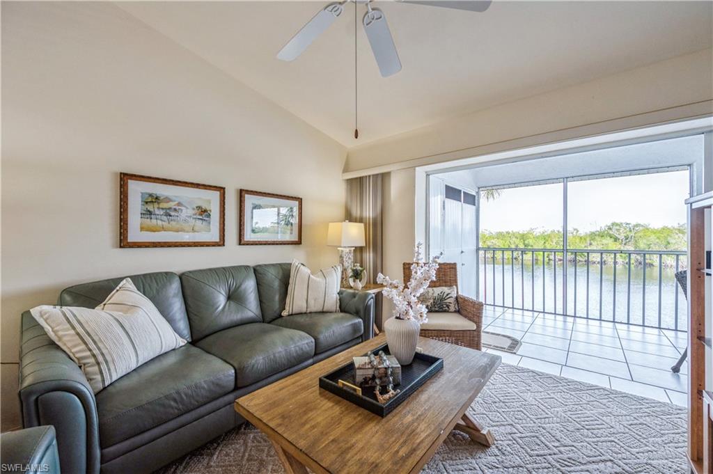 Tiled living area featuring lofted ceiling, a water view, and a ceiling fan