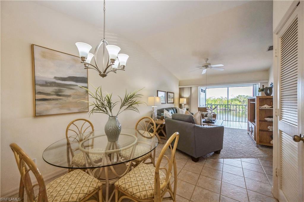Dining space featuring vaulted ceiling, a chandelier, a ceiling fan, and tile patterned flooring