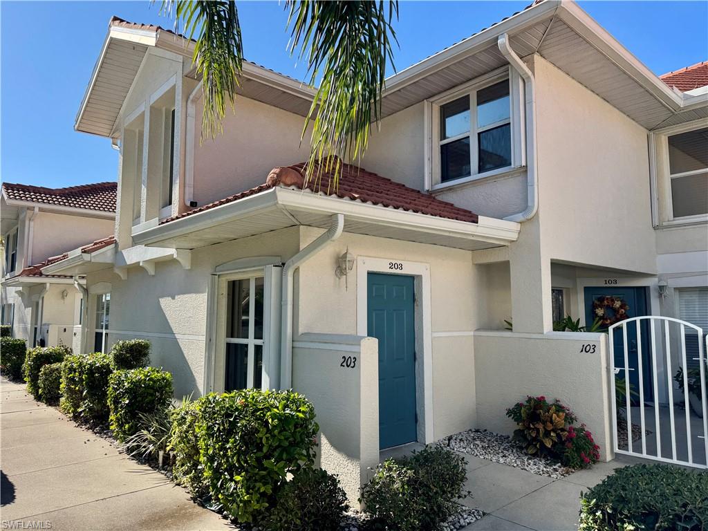 View of front of home featuring a gate, stucco siding, and a tiled roof