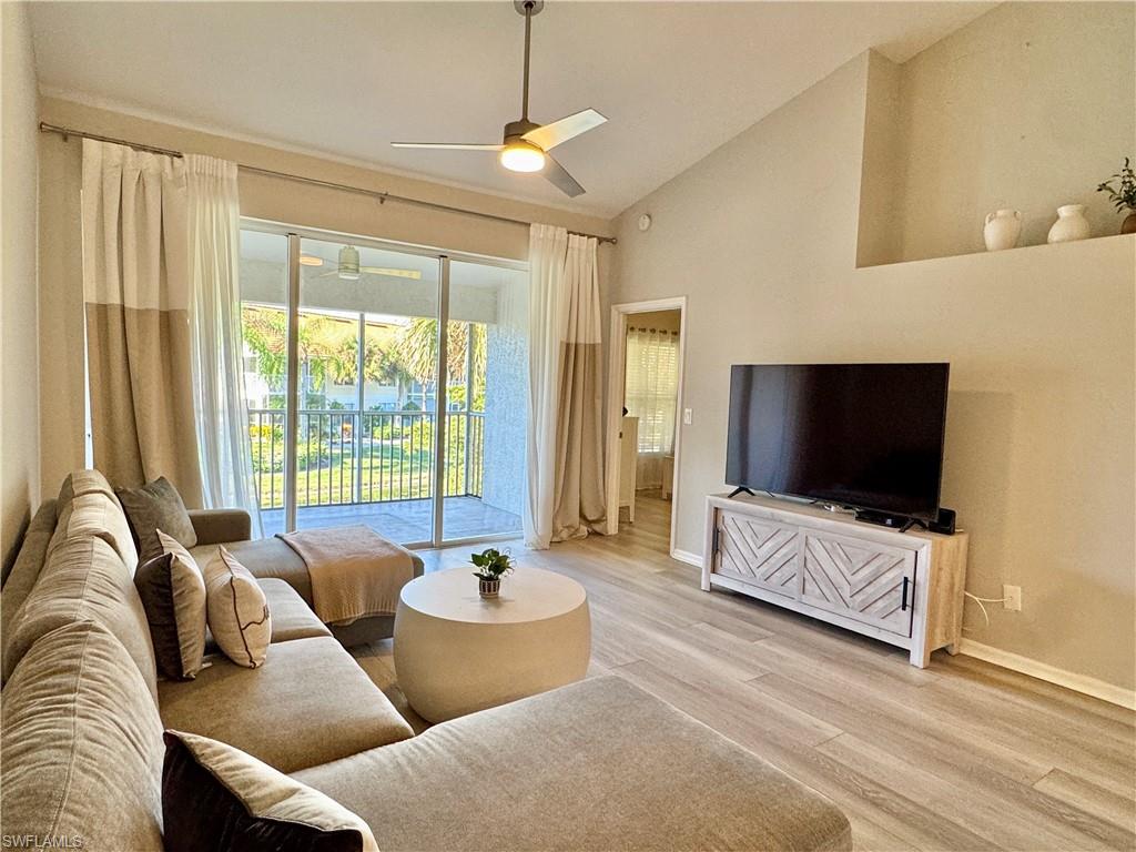 Living room featuring light wood-type flooring, a ceiling fan, and high vaulted ceiling