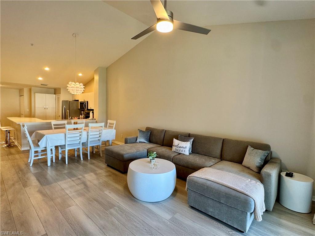 Living room with recessed lighting, light wood-style flooring, and high vaulted ceiling