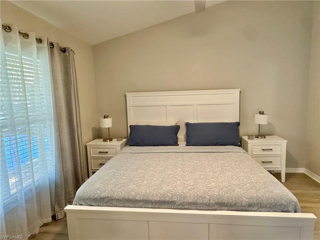 Bedroom with vaulted ceiling and light wood-style floors