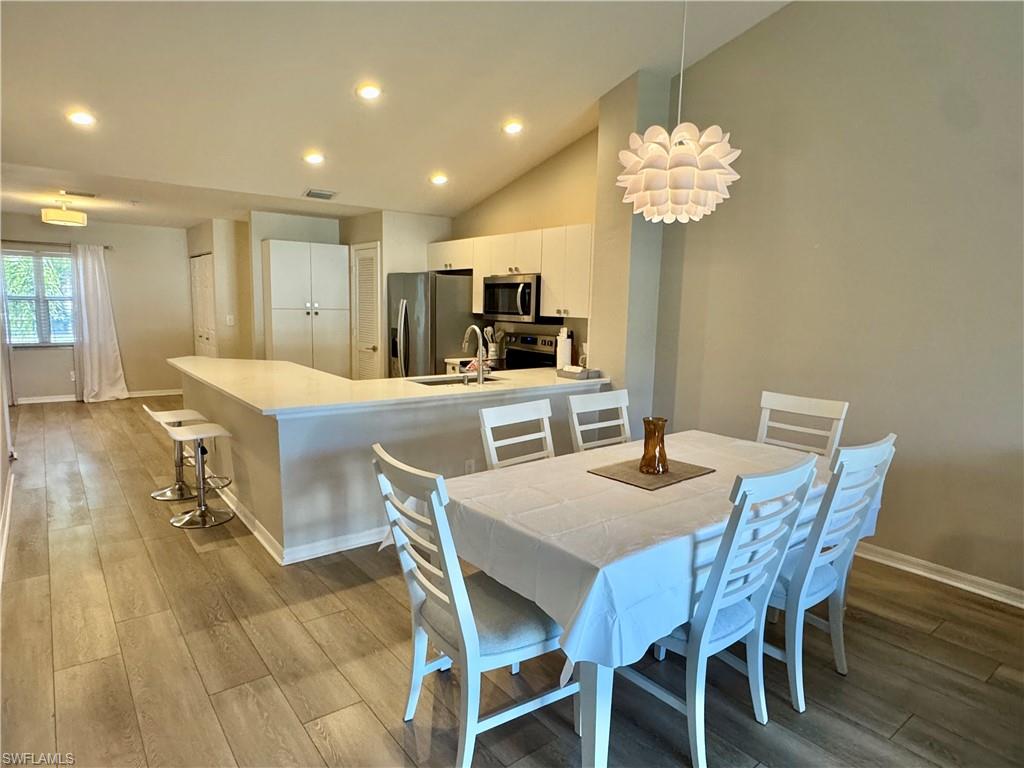 Dining area with light wood-type flooring, high vaulted ceiling, recessed lighting, and a chandelier