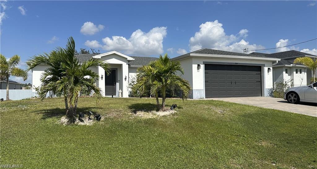 Ranch-style home with a front lawn, stucco siding, driveway, and an attached garage