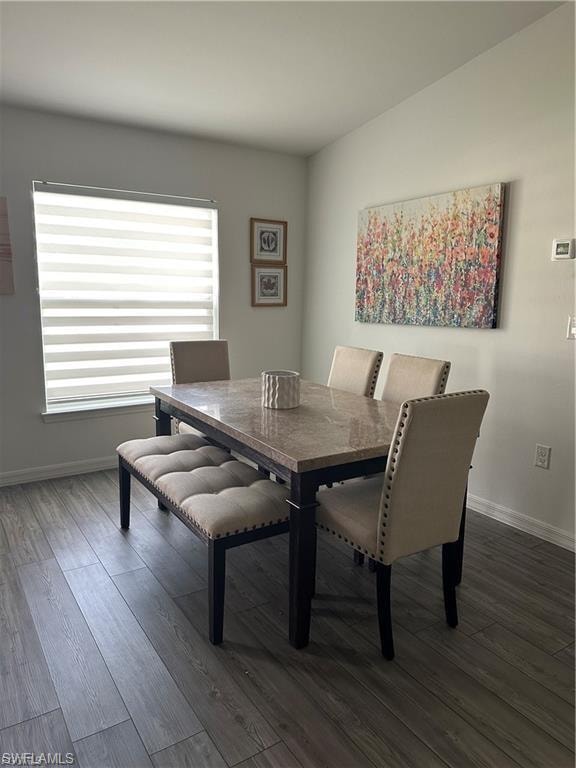 Dining area with dark wood-type flooring and baseboards
