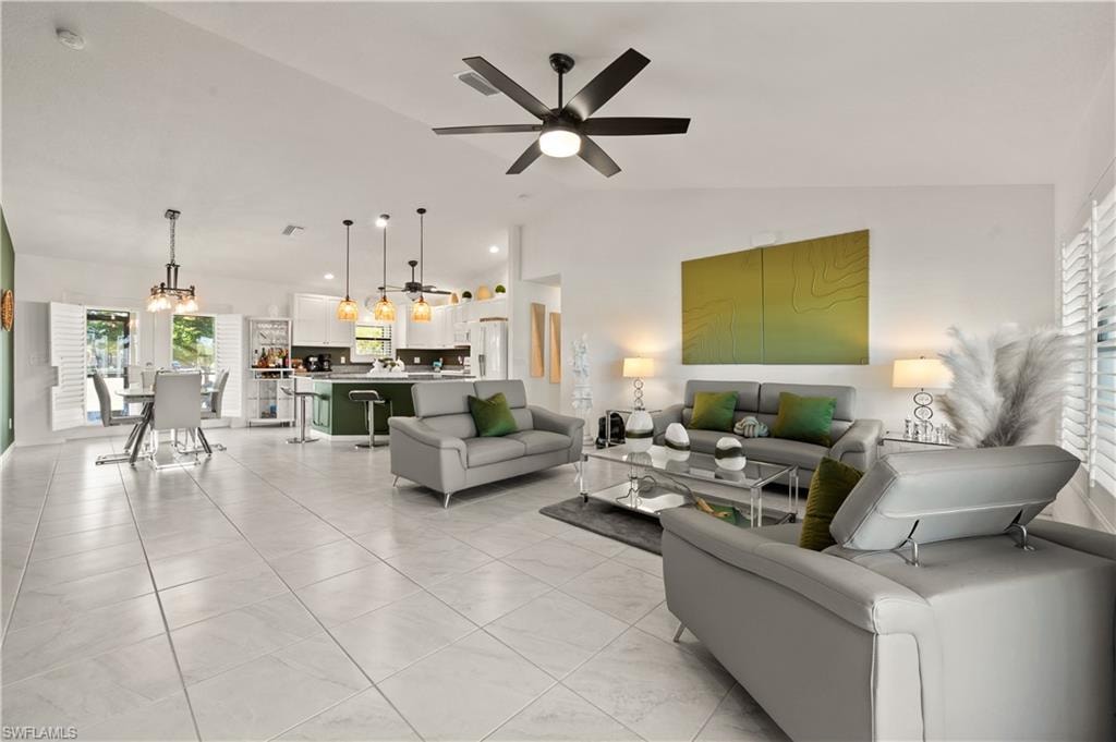 Living area with lofted ceiling, a ceiling fan, and light tile patterned floors
