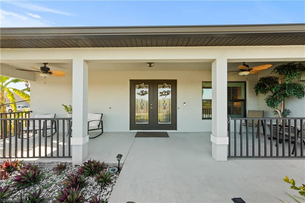 Property entrance with ceiling fan and stucco siding