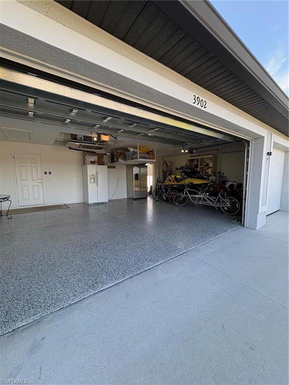 Garage featuring white fridge with ice dispenser and built in refrigerator