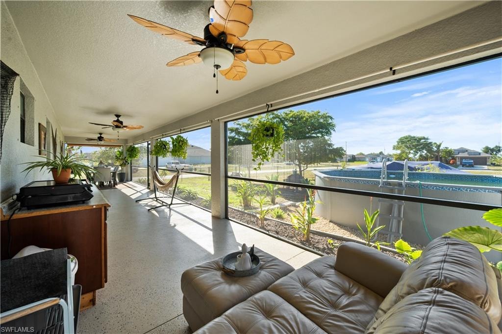 Sunroom featuring a ceiling fan, speckle patterned floor, exterior kitchen, outdoor lounge area, and a textured ceiling