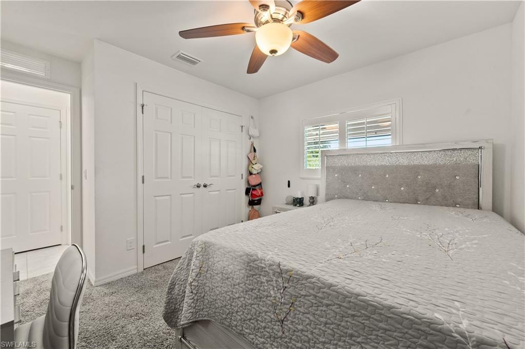 Bedroom featuring ceiling fan, light colored carpet, and a closet