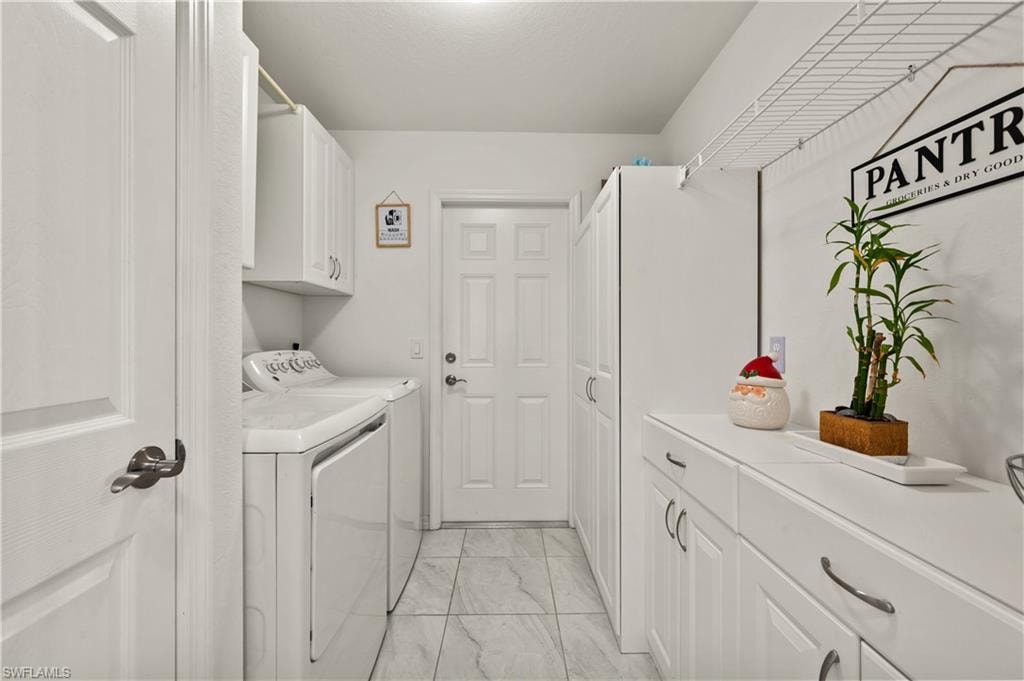 Laundry room with cabinet space, light marble finish flooring, and independent washer and dryer
