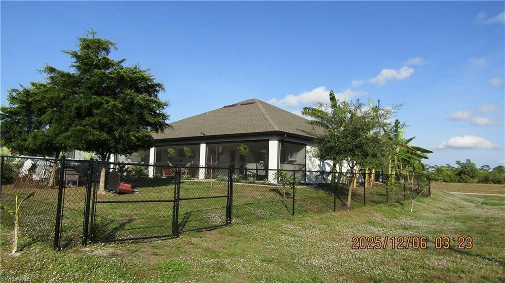 Rear view of house with a gate and a sunroom