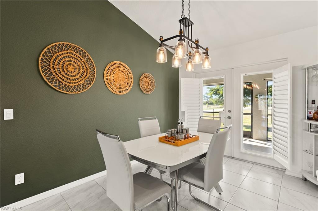 Dining space with french doors, a chandelier, and lofted ceiling