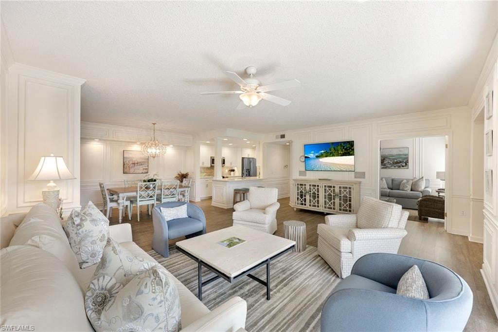 Living area featuring a decorative wall, wood finished floors, a chandelier, and a ceiling fan