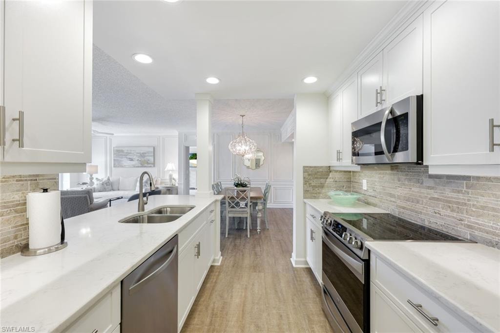 Kitchen featuring backsplash, stainless steel appliances, open floor plan, light stone countertops, and recessed lighting