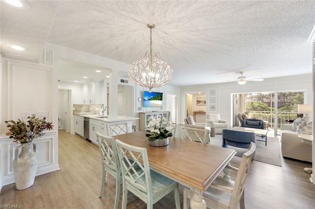 Dining room featuring a decorative wall, a textured ceiling, a chandelier, light wood-type flooring, and ceiling fan
