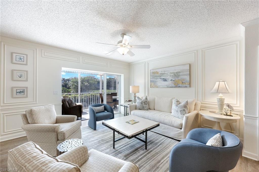 Living area featuring a decorative wall, a ceiling fan, wood finished floors, and a textured ceiling