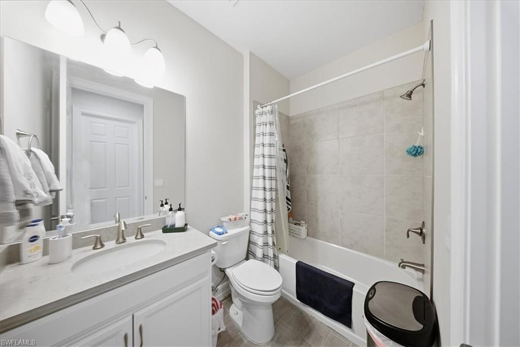Full bathroom with vanity, shower / bath combo with shower curtain, and light wood-style floors