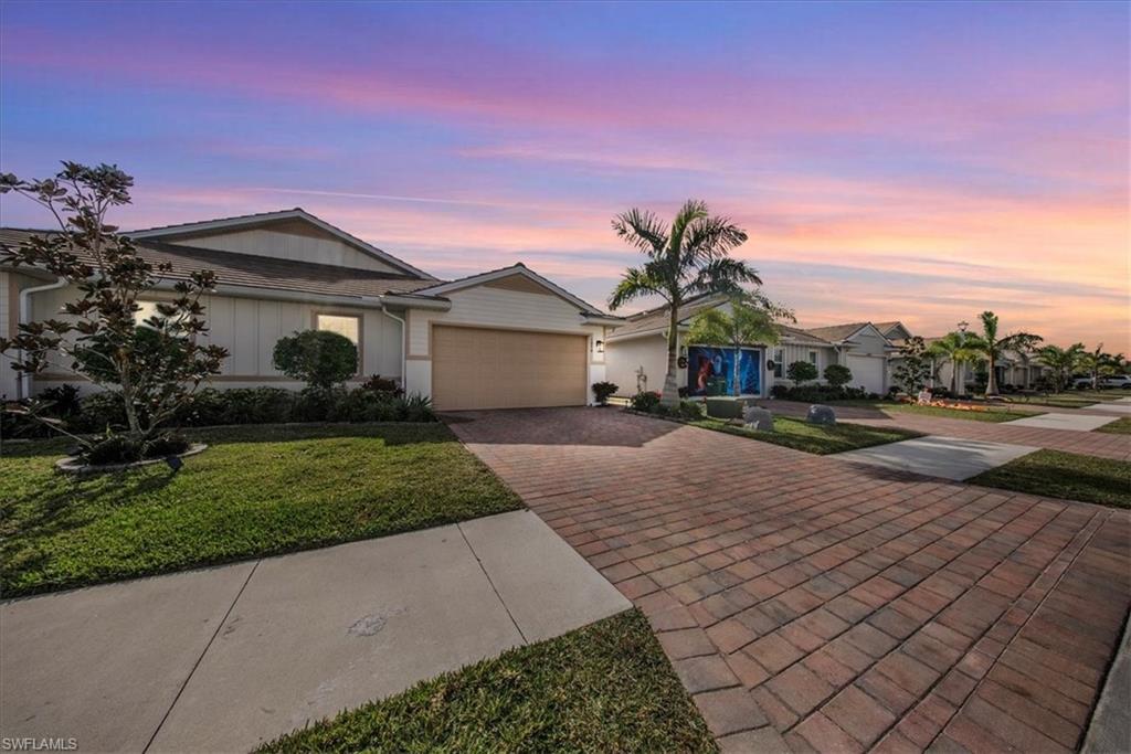 Single story home featuring decorative driveway, a garage, a yard, and board and batten siding