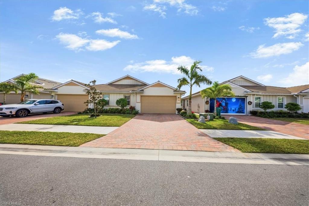 Ranch-style home featuring decorative driveway, a garage, board and batten siding, and a front yard