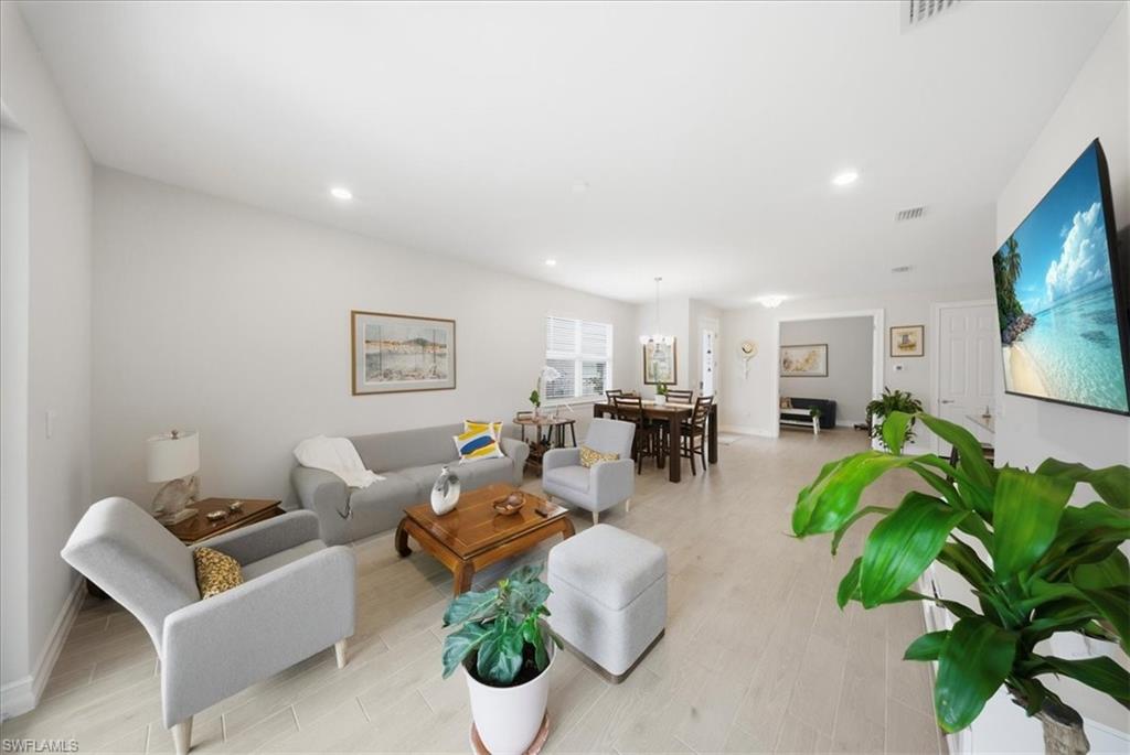 Living area with light wood finished floors and recessed lighting