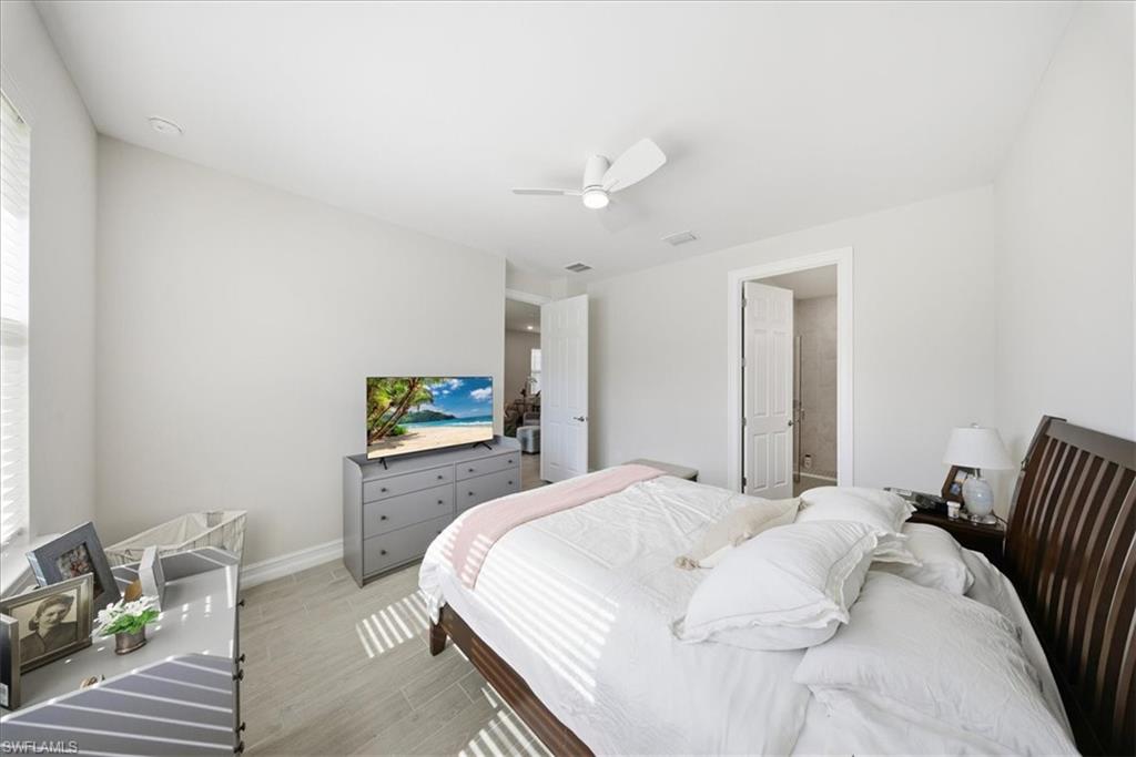 Bedroom featuring wood finished floors, a ceiling fan, and connected bathroom