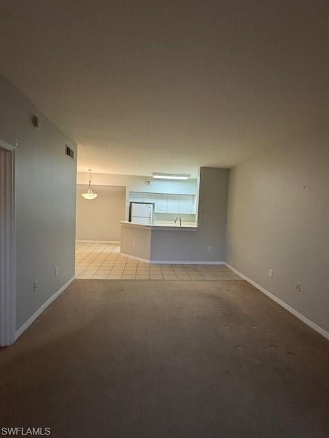 Unfurnished room featuring light colored carpet and light tile patterned floors