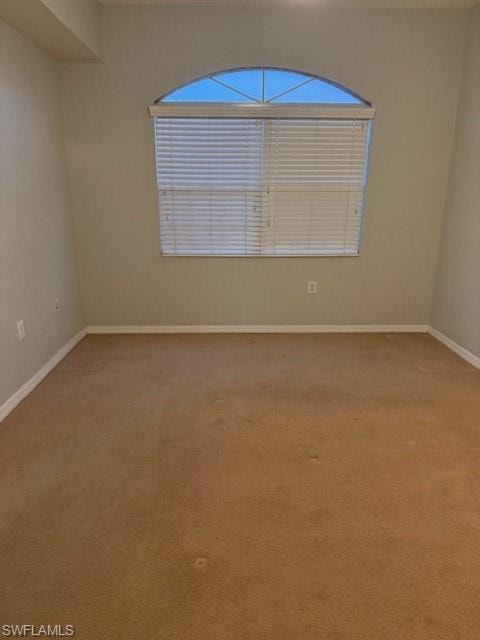 Empty room featuring light carpet and baseboards