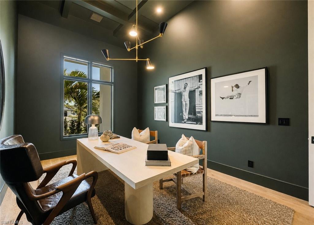 Dedicated room featuring dark green walls, wood-finish flooring, and a modern chandelier