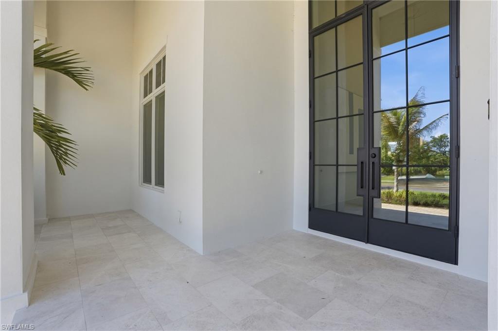The property features a tiled entry area with white walls and a large window, complemented by modern black framed glass entry doors