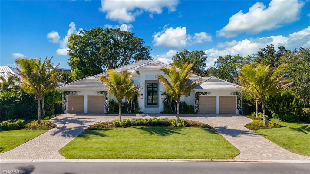 Contemporary-style residence featuring a white stucco exterior, hip roof, and dual two-car garages