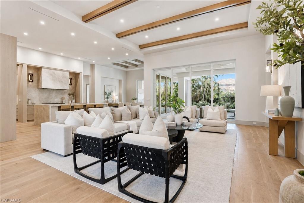 Expansive open-concept living space featuring wood-finish flooring and exposed ceiling beams
