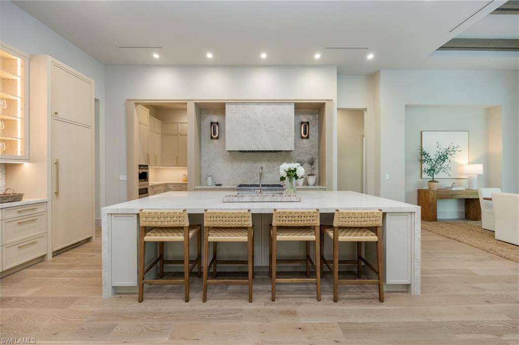 Kitchen with decorative backsplash, light stone countertops, a kitchen bar, and recessed lighting