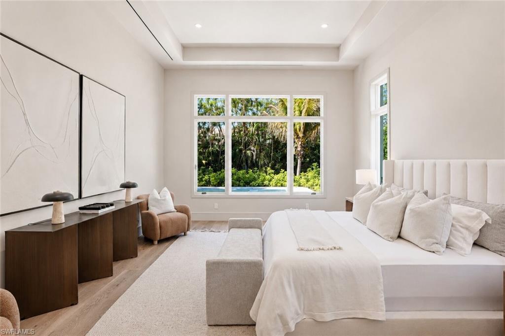 Spacious room featuring light wood-finish flooring, a tray ceiling, and recessed lighting