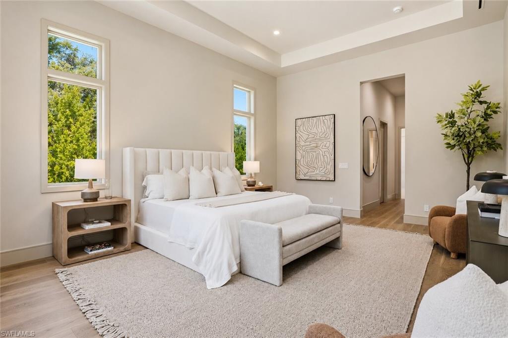 Expansive room featuring wood-finish flooring, a recessed ceiling, and multiple tall windows