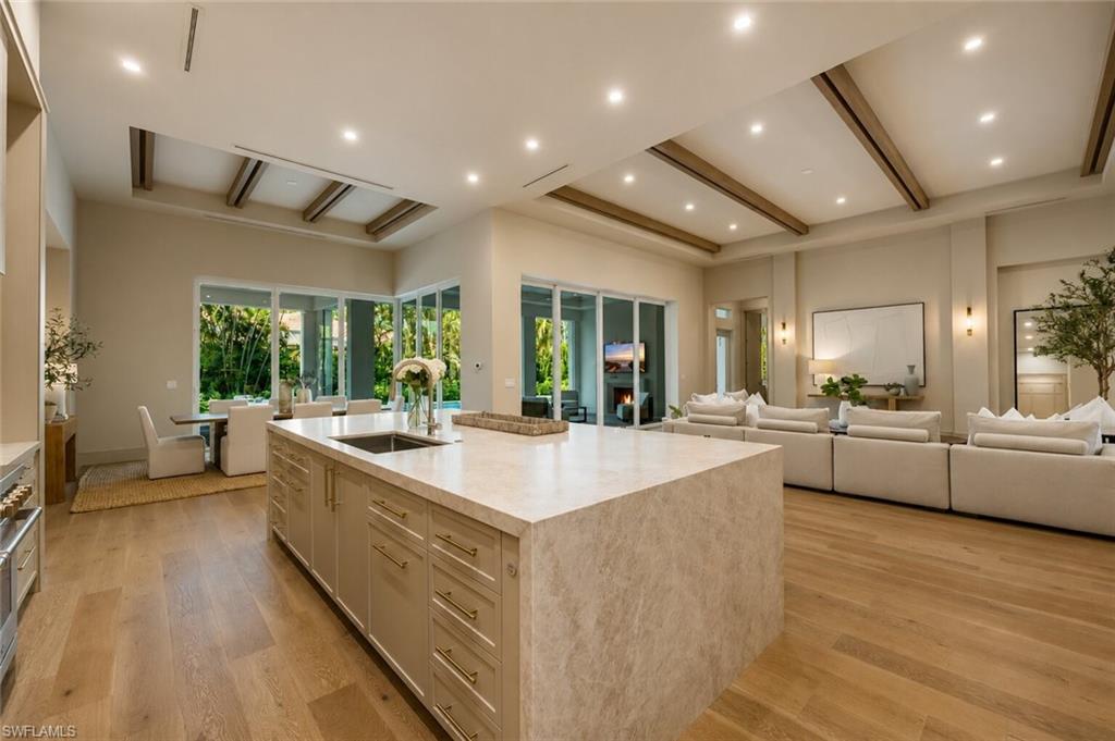 Expansive kitchen island featuring an undermount sink, ample storage cabinetry, and integrated architectural lighting
