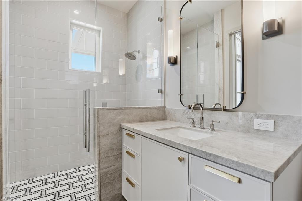 Full bath with vanity, a shower stall, and tile walls