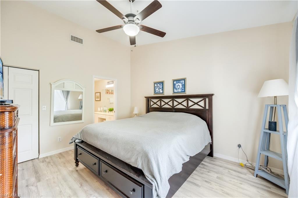 Bedroom with light wood finished floors, a ceiling fan, and ensuite bath
