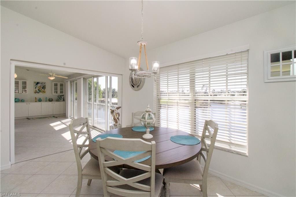 Dining space with ceiling fan with notable chandelier, light tile patterned flooring, and lofted ceiling